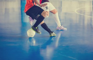 Indoor soccer sports hall. Football futsal player, ball, futsal floor. Sports background. Youth futsal league. Indoor football players with classic soccer ball.